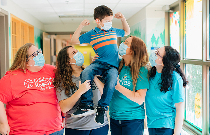 Young boy patient flexing muscles on shoulders of nursing staff