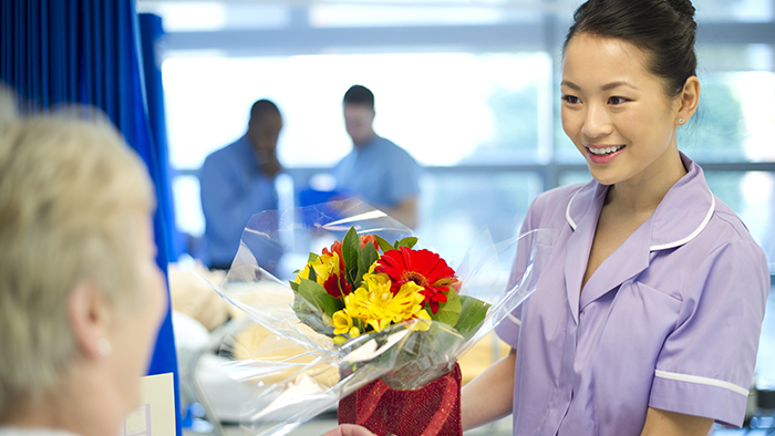 Volunteer bringing flowers to patient in hospital