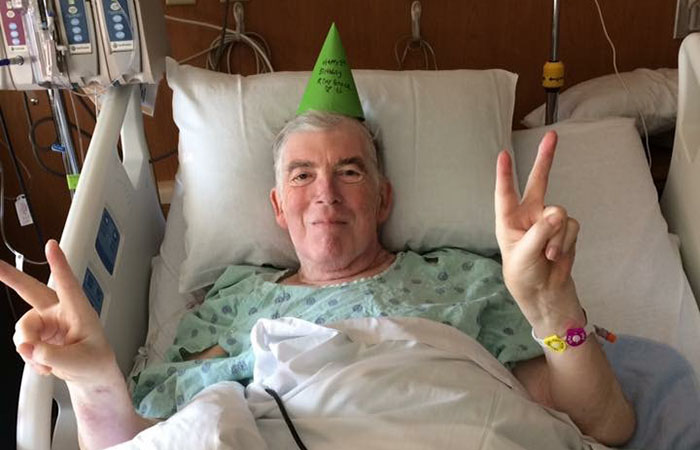 Robert sitting in a hospital bed wearing a party hat