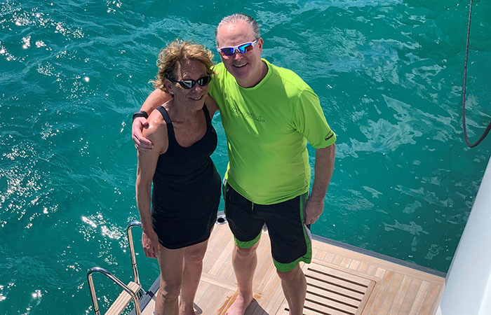 Lori and her husband standing on a dock smiling