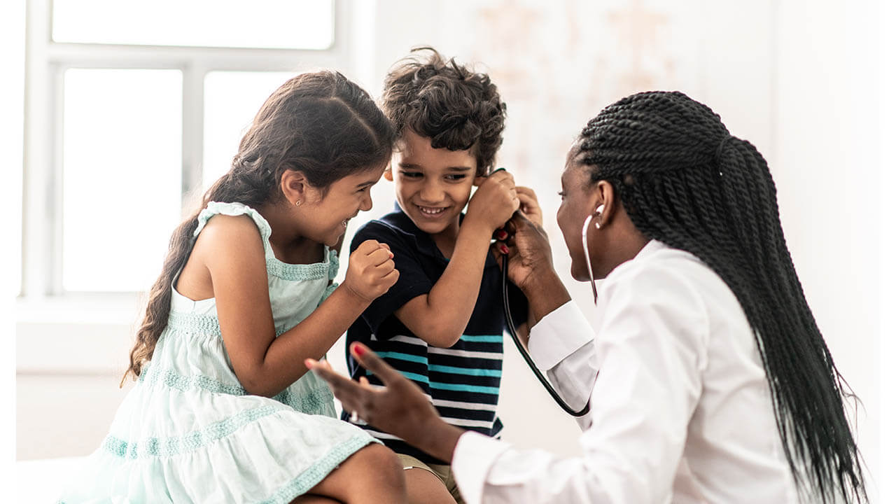 Young female nurse sitting talking with two children