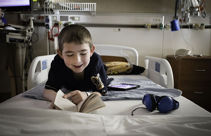 Quentin reading a book in a hospital bed at HSHS St. Vincent Children's Hospital in Green Bay