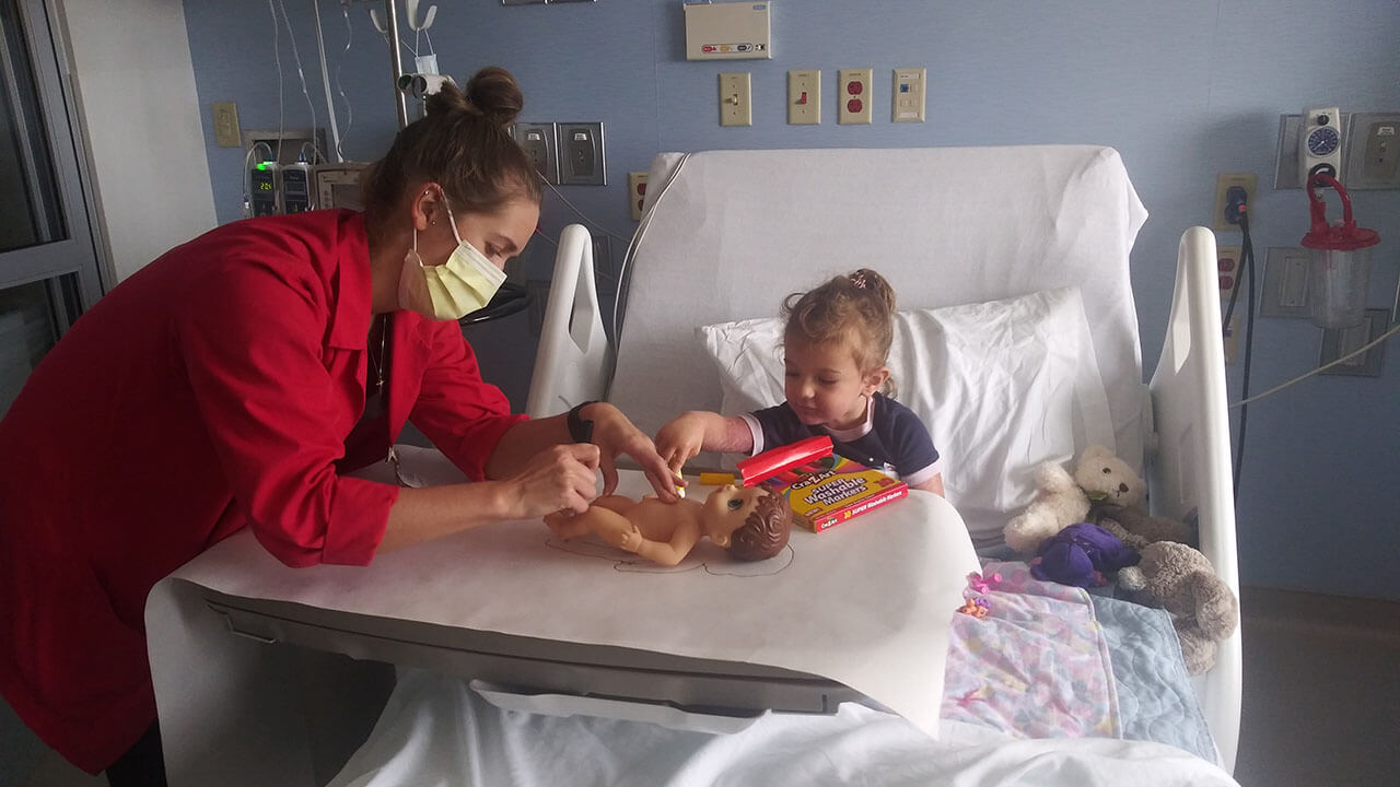 Rosalind sitting in a hospital bed coloring