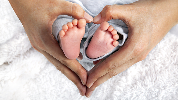 A mother's hand holding baby's feet in shape of a heart