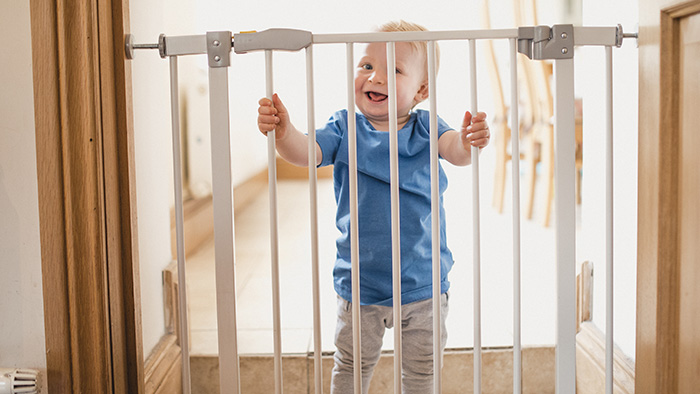 Baby boy holding onto safety gate