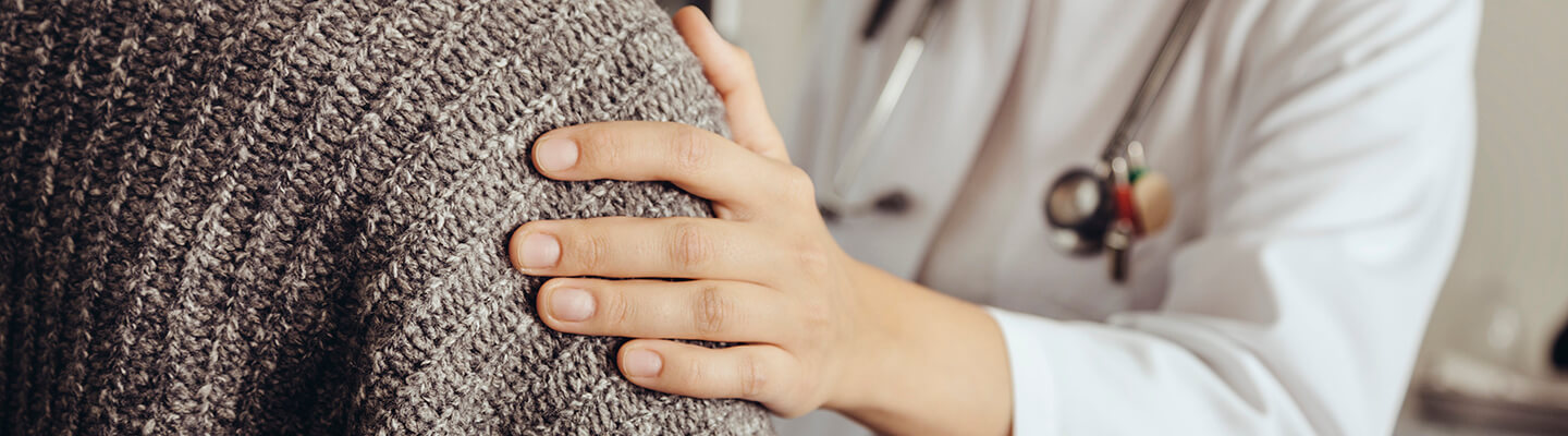 A close up of a care provider and patient holding hands