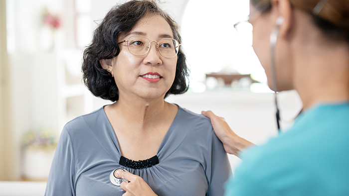 Female doctor examining the heart of female patient with a stethoscope