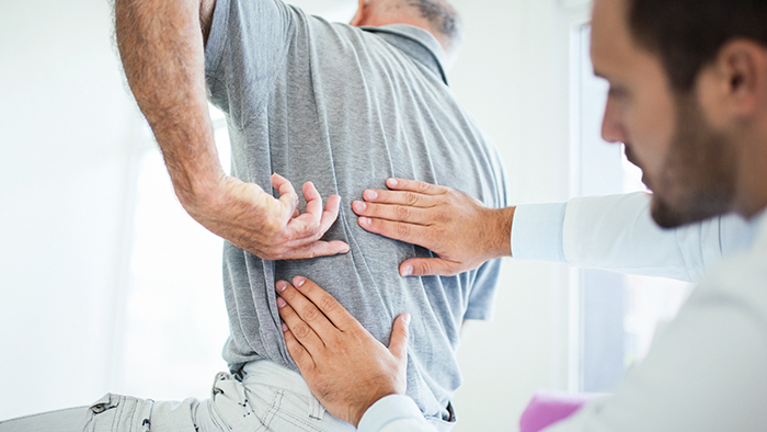 Male doctor looking at the back of a patient