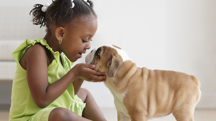 Young girl with puppy giving it a kiss