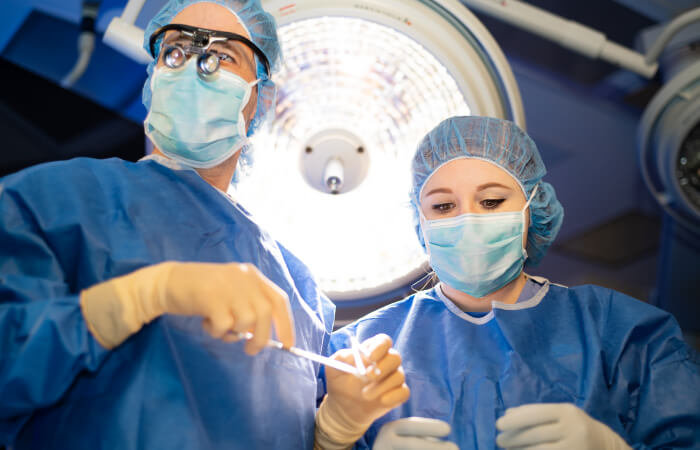 A male and female surgeon looking down at patient