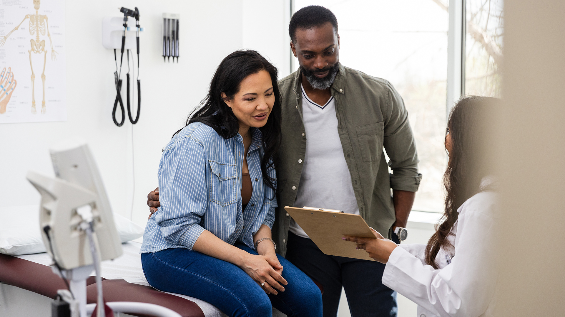 woman and man speak to doctor in doctor's office