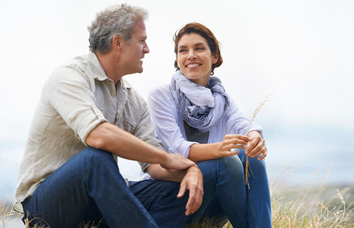 older couple sitting out in grass field 