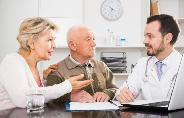 Doctor talking to two elderly patients in a hospital setting