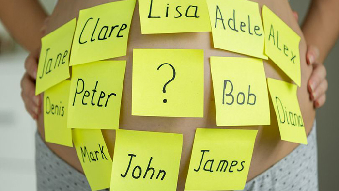 Baby names on sticky-notes on pregnant woman's belly