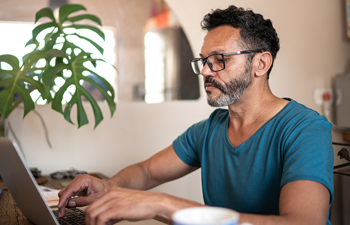 middle aged hispanic male using laptop at desk