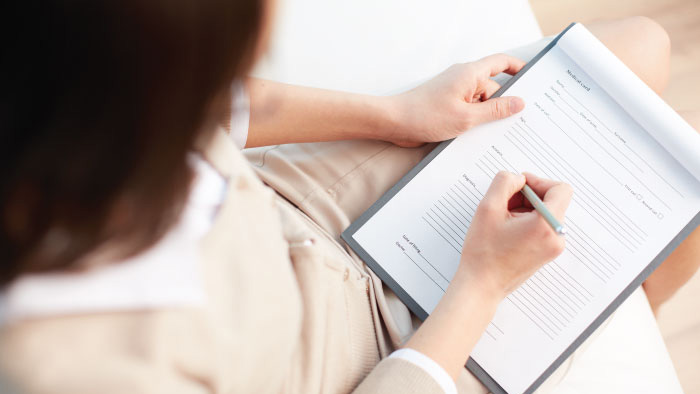 Woman with pen in hand holding clipboard