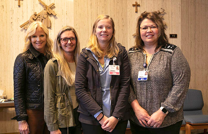 Four women wearing medical badges posing for a picture in a church.